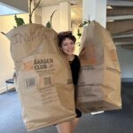 Smiling figure carrying two filled leaf bags