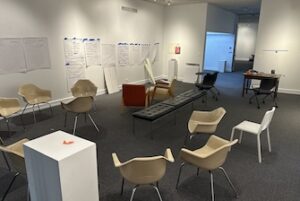 room with chairs, a pedestal, taped pages on the wall