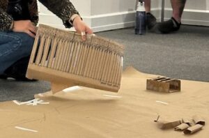 photo of a students hands displaying a brown paper maquette of drawn arches