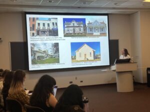 Students in a classroom watch as visiting lecturer Lindsey Walsworth presents a screen presenting restoration examples