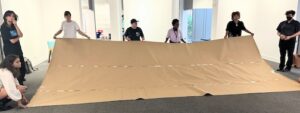 Students holding a 20 foot sheet of brown paper in the Dalton gallery