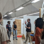 students standing on the third floor of Dana Fine Arts building listening to information from visiting lecturerer Scott Englin