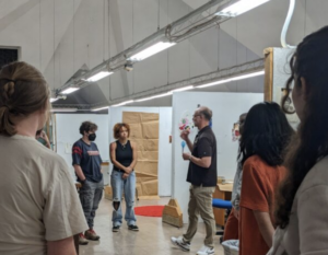 students standing on the third floor of Dana Fine Arts building listening to information from visiting lecturerer Scott Englin