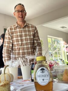 Peter Helfrich smiling above a table with honey