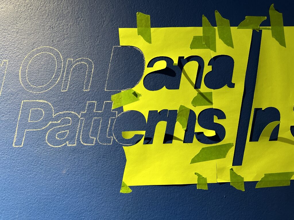 outlines of text (exhibition title) on blue wall: Building on Dana / Patterns in Space
