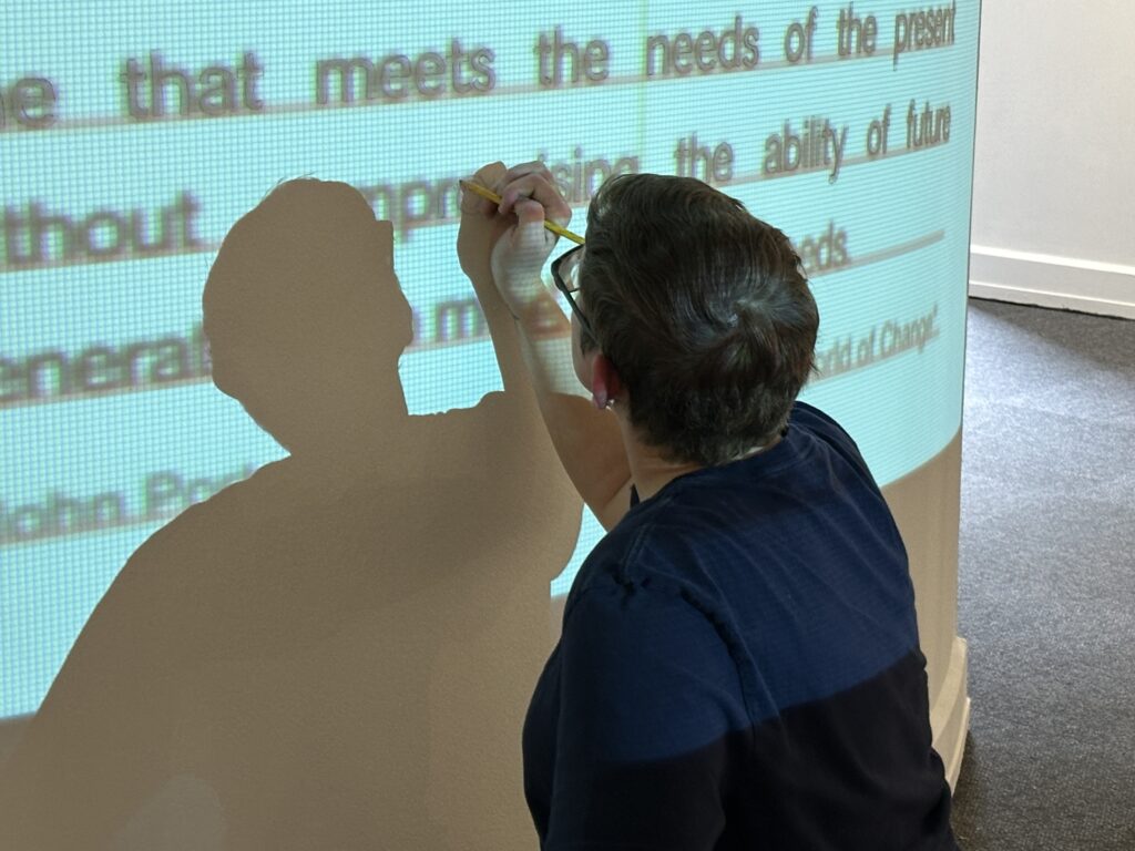 person tracing projected text on a wall
